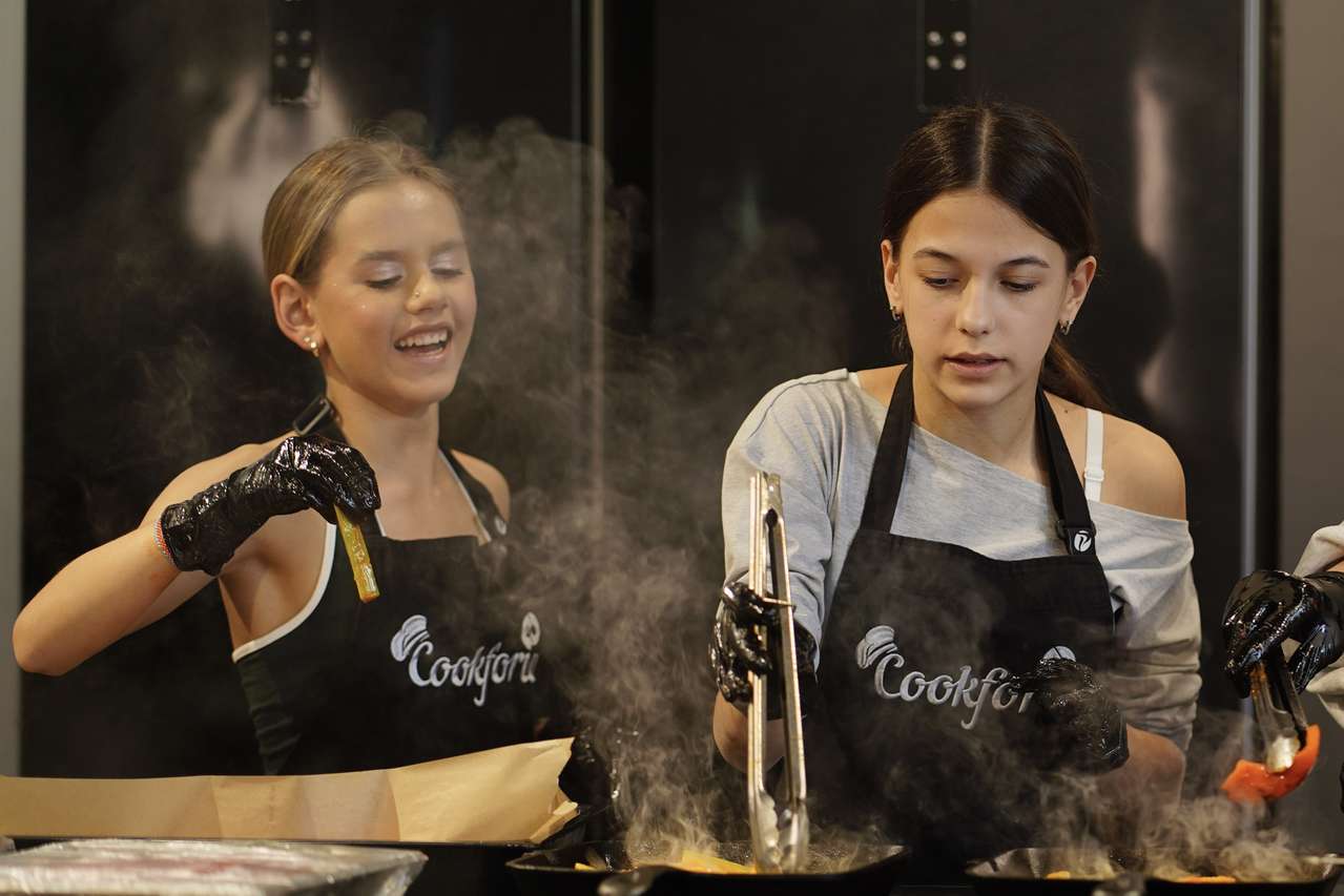 Две участницы мастер-класса Cookforia готовят у плиты