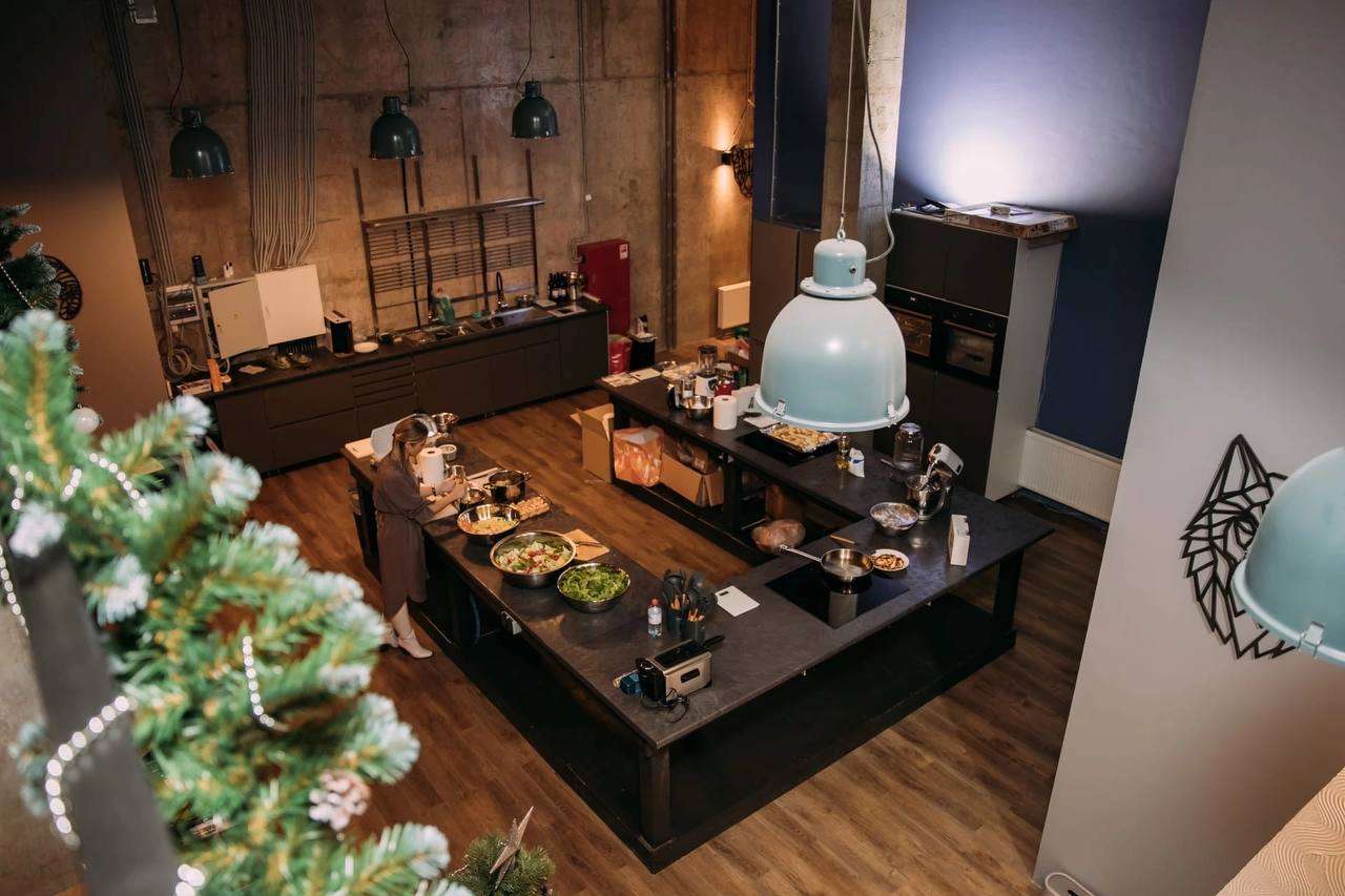 Кухня студии Cookforia с блюдами на рабочем острове и новогодней елкой